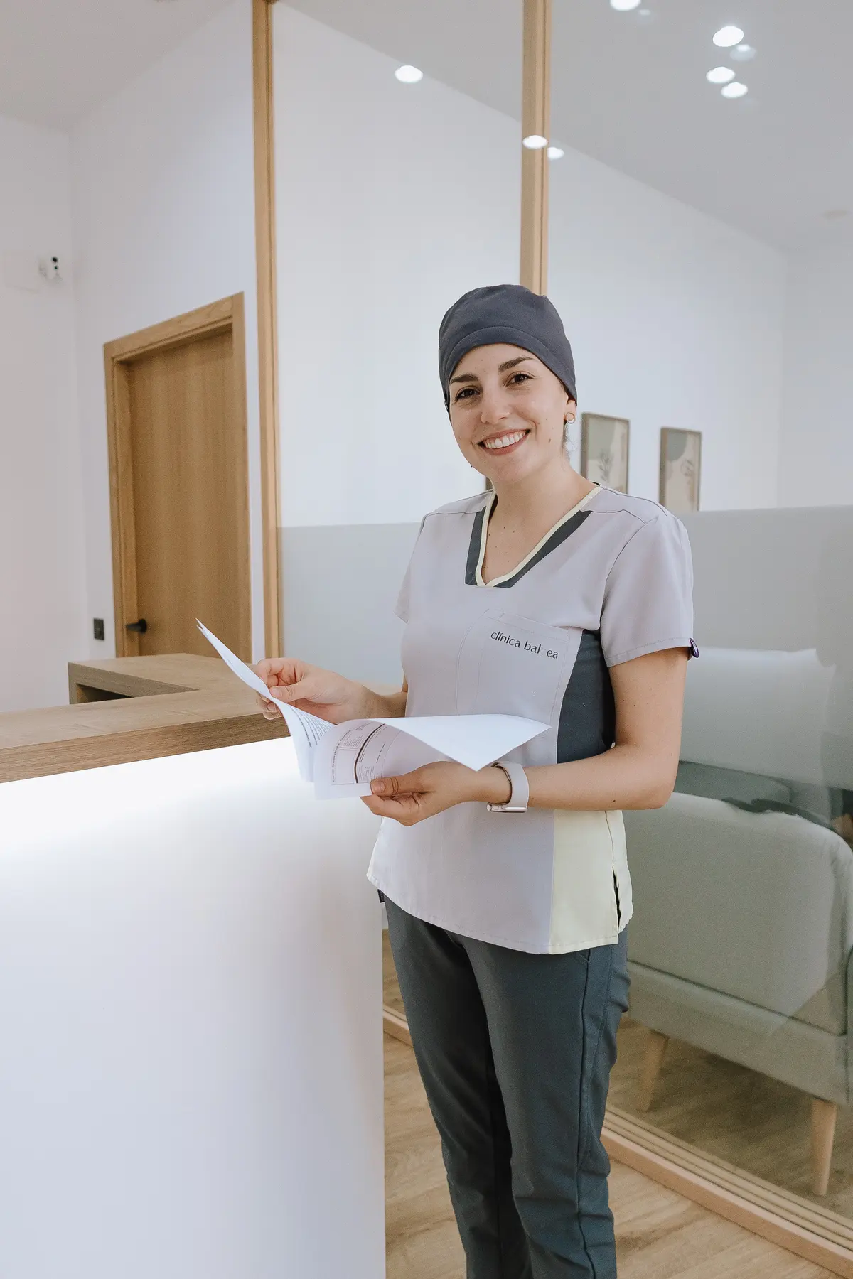 Recepcionista de Clínica Balbea sonriendo con documentación de un paciente